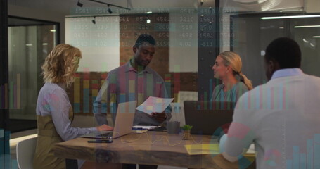 Collaborating office team typing, reviewing documents around wooden conference table with succulent