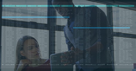 Collaborating office professionals analyzing data on transparent glass panel in meeting room