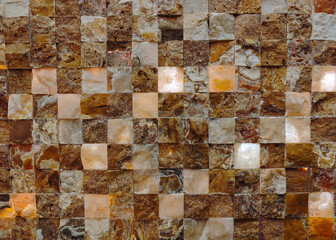 A wall made of brown tiles with a light shining on it