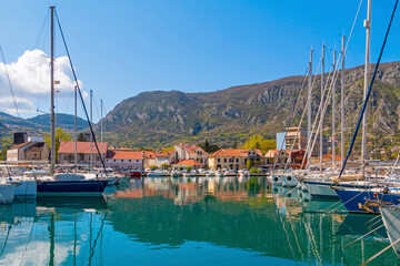 Kotor Bay shines under the sun as elegant yachts drift on crystal-clear waters, with the historic...