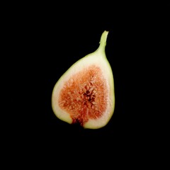 Artistic photograph featuring a sliced fig set against a dark background. The vibrant red flesh are...