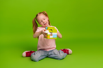 Cute young girl building with colorful blocks on green background, showcasing playful imagination...