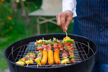 Grilling skewers and sausages on barbecue grill outdoors