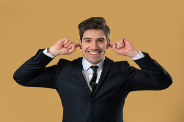 Businessman covering ears on in beige studio. Smiling man in suit look to camera