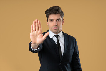Portrait of serious businessman in professional suit showing rejecting gesture by stop palm sign....