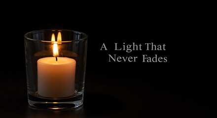 Candle glowing softly in glass holder on black background  