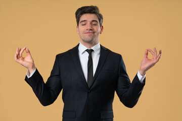 Calm businessman in formal suit relaxing, meditating. Handsome european man calms down, breathes deeply with mudra om. Studio footage.