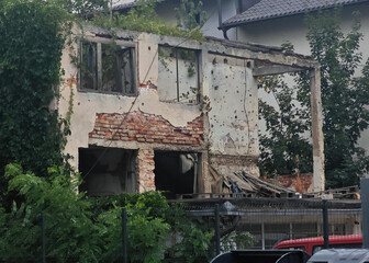 A building with a lot of damage and a red truck parked in front of it