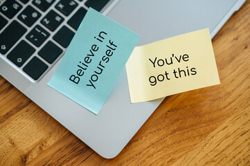 Believe in yourself reminder on sticky note, motivational message on laptop keyboard