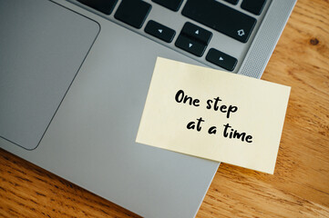 One step at a time sticker on laptop, motivational support in business setting