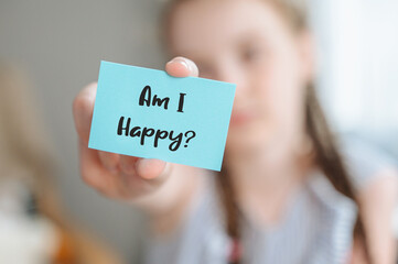 girl holding a note with the question am i happy