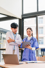 Two healthcare professionals, one male and one female, discussing patient information on digital tablet in modern medical office, teamwork and collaboration, natural light