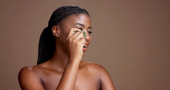 Woman, gua sha and smile in studio for beauty, circulation and product for skincare by background. African girl, model and happy for stone tools, cosmetics or mock up space for dermatology in Nigeria