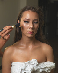 Beautiful woman with red lipstick and golden hoop earrings smiles softly. She wears a white dress...