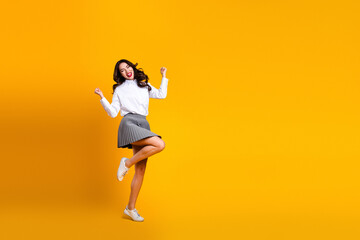 Fototapeta premium Young fashionable woman in white shirt and skirt posing with enthusiasm against a bright yellow background
