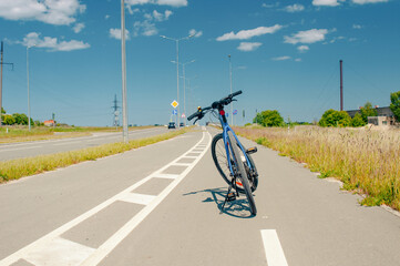 Bicycle at bike path in country near roadway in summer