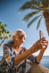 An elderly happy  woman with a mobile phone, relaxing outdoors
