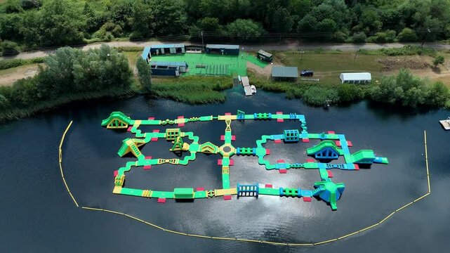Aerial close up drone shot beautiful blue lakes and lush greenery with inflatable aqua water park play event near Little Paxton England UK