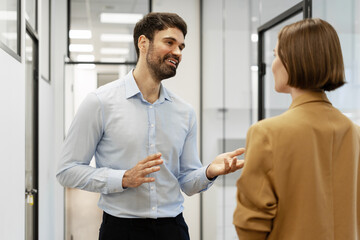 Businessman explaining something to his colleague in the office corridor