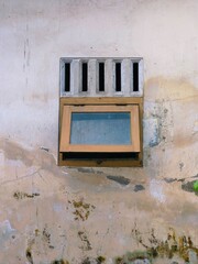 wooden windows with old-style air vents with walls that are worn and little moldy