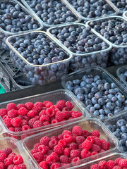 Market Display of Fresh Blueberries and Raspberries in Plastic Containers