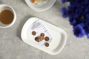 Tips, receipt, dirty plate and cup on grey table, flat lay