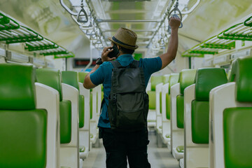 Stay connected while traveling. Rear view passenger man tourist in backpack on the train mrt...
