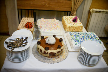 Different types of birthday cakes on the table next to the plates ready to be served