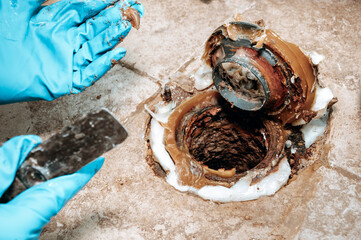 Detailed image of the toilet base area with wax ring placement during plumbing maintenance with...