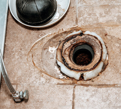 Close-up image showing the process of replacing the wax ring under a toilet with copy space.