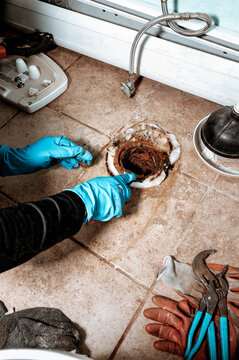 Close-up view of a Professional plumber replacing old wax ring seal before toilet installation, with copy space.