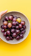 Close-cropped image of fresh grapes held in a porcelain bowl. The background is solid and simple, highlighting organic color, texture, and clean, elegant fruit presentation.
