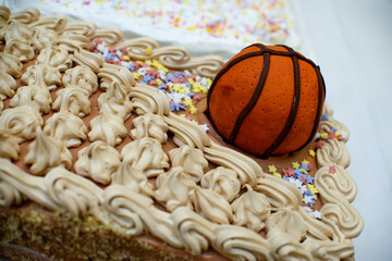 Chocolate cake that is decorated with chocolate cream, colorful stars and a figure made in the shape of a basketball