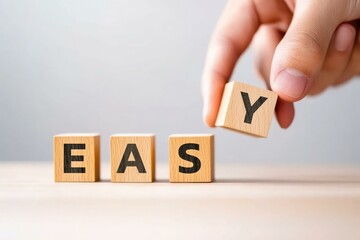 A close-up image of a hand placing the letter 'Y' onto wooden blocks spelling 'EASY', illustrating simplicity and ease in learning or tasks, perfect for educational or motivational materials.