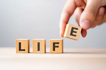 A hand arranging wooden blocks to spell LIFE, symbolizing creativity, growth, and the importance of positive thinking in everyday life.