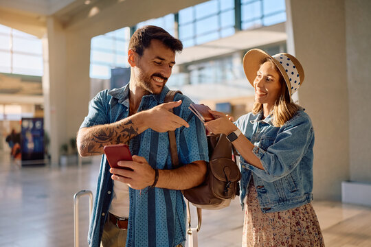 Happy couple of tourists using passports while checking in at airport departure terminal. - Powered by Adobe