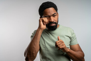 Black man rubbing eyes with discomfort, irritated and tired, experiencing eye itching and burning, eye health concept.