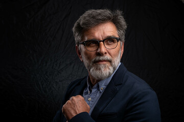 Portrait of handsome man in a studio on a dark background. Handsome man posing. Middle-aged good...