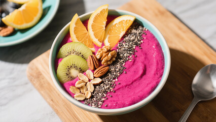 A vibrant smoothie bowl with colorful fruit and nuts, ready to eat.