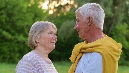 A loving senior couple gazes at each other with affection in a natural outdoor setting, sharing a tender moment.