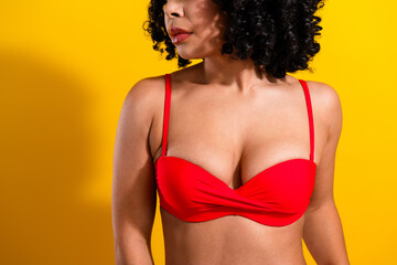 Stylish woman in red bikini against a vibrant yellow backdrop showcases beauty, confidence, and...