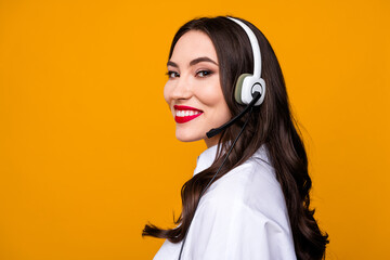 Charming female customer service representative with headset and trendy white shirt posing against...