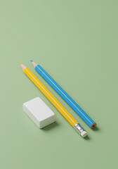 Yellow and blue pencils with eraser on a green background.