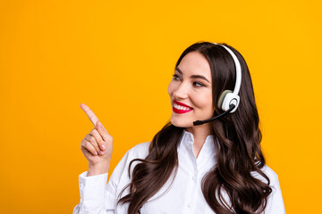 Professional woman with headset pointing to the left against a bright yellow background, showcasing...