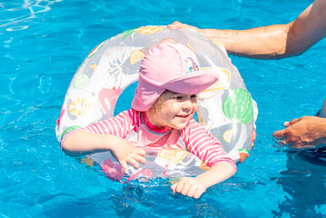 Family Dad and Daughter Swim in Pool on Sunny Day in Summer with Inflatable Ring
