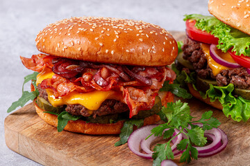 two burgers with beef patty, fried bacon, cheddar cheese, tomatoes, homemade, no people,