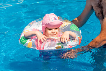 Family Dad and Daughter Swim in Pool on Sunny Day in Summer with Inflatable Ring