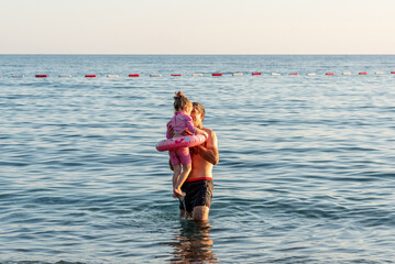 Family father and daughter swim sea on sunny summer day, man teach girl to swim