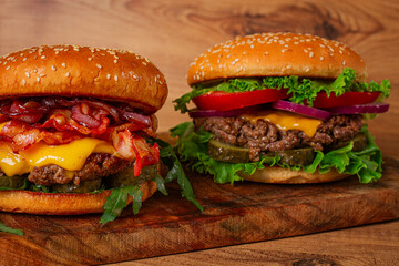 two burgers with beef patty, fried bacon, cheddar cheese, tomatoes, homemade, no people,
