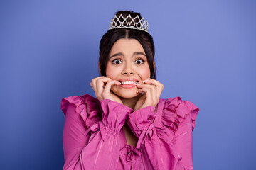 Glamorous young woman in a ruffled outfit with a crown looking expressive against a vibrant backdrop, full of life